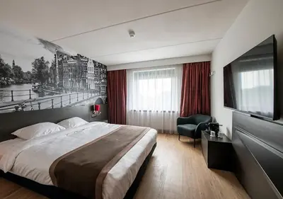 a hotel room with a bed and a flat screen tv at Bastion Hotel Amsterdam Noord in Amsterdam