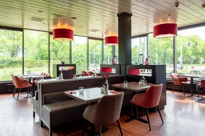 a restaurant with tables and chairs and large windows at Bastion Hotel Amsterdam Noord in Amsterdam