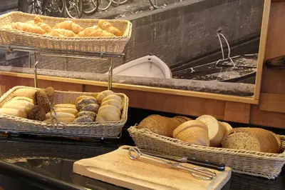 a bunch of breads in baskets on a counter at Bastion Hotel Amsterdam Zuidwest in Amsterdam