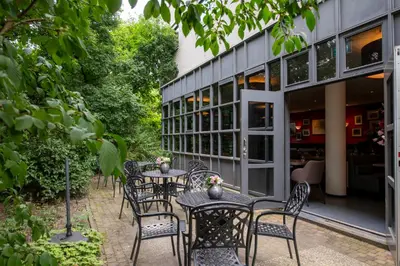 a patio with tables and chairs in front of a building at Bastion Hotel Amsterdam Zuidwest in Amsterdam