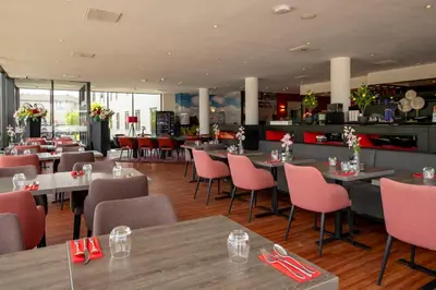 a restaurant with tables and chairs and a bar at Bastion Hotel Zaandam in Zaandam