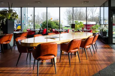 a large wooden table and chairs in a restaurant at Bastion Hotel Zaandam in Zaandam