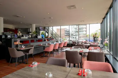 a restaurant with tables and chairs and windows at Bastion Hotel Zaandam in Zaandam
