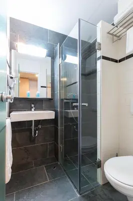 a bathroom with a shower and a sink and a toilet at Bastion Hotel Zaandam in Zaandam