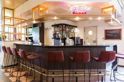 a bar in a restaurant with red stools at Bastion Hotel Bussum Hilversum in Bussum