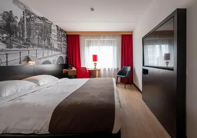 a bedroom with a large bed and red curtains at Bastion Hotel Bussum Hilversum in Bussum