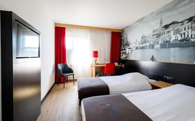 a hotel room with two beds and a tv at Bastion Hotel Haarlem Velsen in Santpoort-Noord