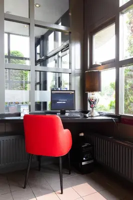 a red chair sitting at a desk with a computer at Bastion Hotel Leiden Oegstgeest in Oegstgeest