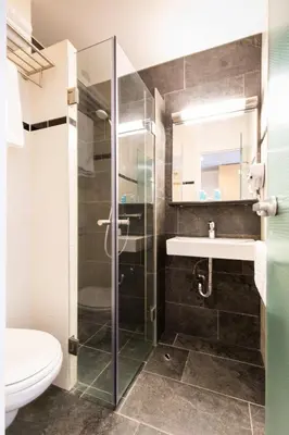 a bathroom with a shower and a sink and a toilet at Bastion Hotel Leiden Oegstgeest in Oegstgeest