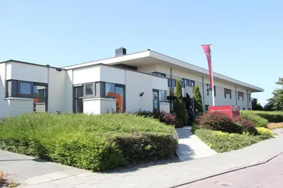 a white building with bushes in front of it at Bastion Hotel Leiden Oegstgeest in Oegstgeest