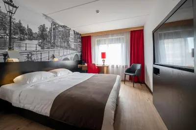 a bedroom with a large bed and a television at Bastion Hotel Leiden Voorschoten in Leiden