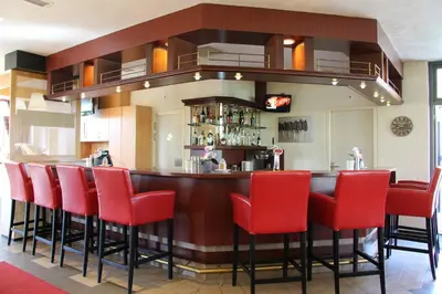 a bar in a restaurant with red chairs at Bastion Hotel Leiden Voorschoten in Leiden