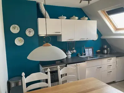 a kitchen with white cabinets and a blue wall at 'Onder-dak' 2-persoons appartement in Zandvoort