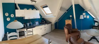 a kitchen with blue walls and a table and chairs at 'Onder-dak' 2-persoons appartement in Zandvoort