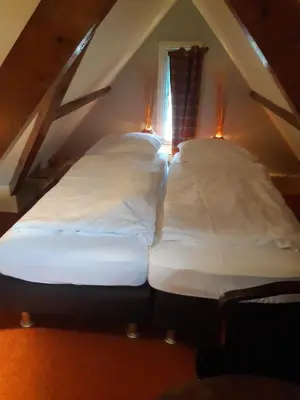 two beds in a attic with two lights on them at Villa Zomerdijk in Velsen-Zuid
