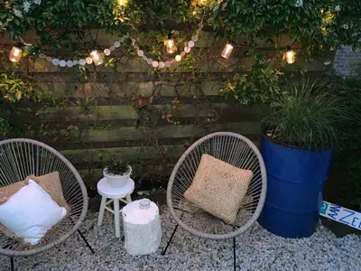 a patio with three chairs and a table and plants at Meerpaal 43 Bergen in Bergen