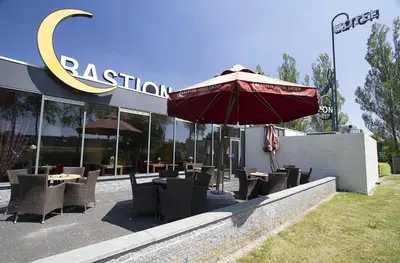 a restaurant with tables and chairs and an umbrella at Bastion Hotel Schiphol Hoofddorp in Hoofddorp
