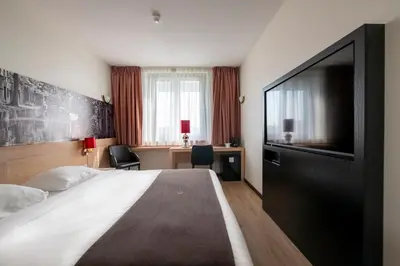 a hotel room with a bed and a flat screen tv at Bastion Hotel Utrecht in Utrecht