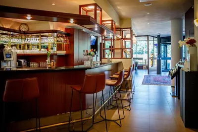 a bar with orange stools in a restaurant at Bastion Hotel Utrecht in Utrecht