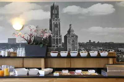 a counter with plates of food and a clock tower at Bastion Hotel Utrecht in Utrecht