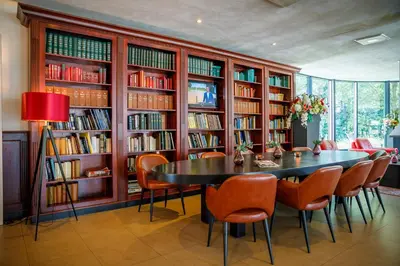 a dining room with a table and chairs and bookshelves at Bastion Hotel Utrecht in Utrecht