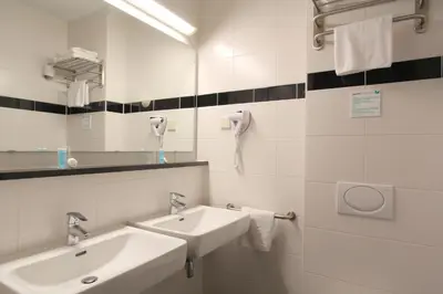 a bathroom with two sinks and a mirror at Bastion Hotel Utrecht in Utrecht