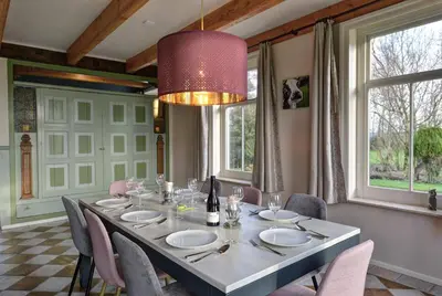 a dining room with a table with chairs and a chandelier at Vakantiehuis Overleek in Monnickendam