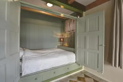 a small bedroom with a bed and an open door at Vakantiehuis Overleek in Monnickendam