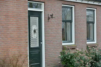 a brick house with a black door with a window at Vakantiehuis Overleek in Monnickendam