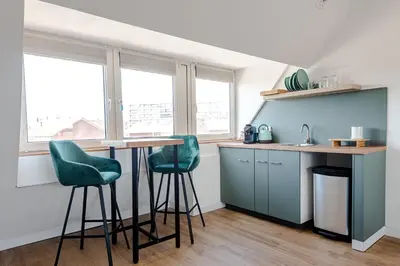 a kitchen with blue cabinets and green stools at Albatros aan Zee - Studio in Zandvoort