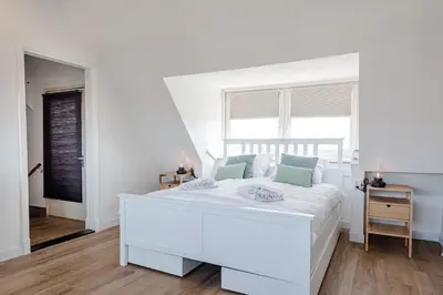 a white bedroom with a white bed and a window at Albatros aan Zee - Studio in Zandvoort
