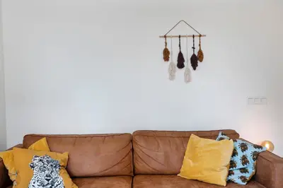 a living room with a brown couch with yellow pillows at Amsterdam Dunes Holiday Home in Zandvoort