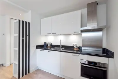 a kitchen with white cabinets and a sink at Amsterdam Dunes Holiday Home in Zandvoort