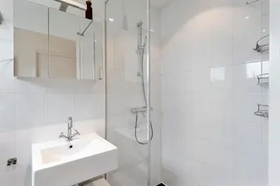 a white bathroom with a sink and a shower at Amsterdam Dunes Holiday Home in Zandvoort