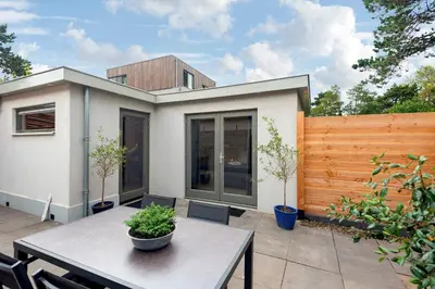 a patio with a table and a fence at Amsterdam Dunes Holiday Home in Zandvoort