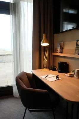 a desk with a chair and a lamp on it at Two Brothers Noordwijk Beach in Noordwijk aan Zee