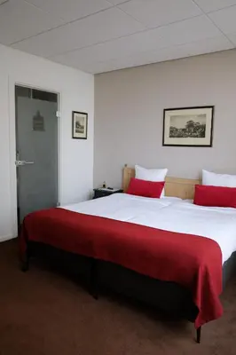 a bedroom with a large bed with red pillows at Two Brothers Noordwijk Beach in Noordwijk aan Zee