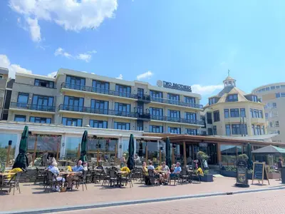 a group of people sitting at tables in front of a building at Two Brothers Noordwijk Beach in Noordwijk aan Zee