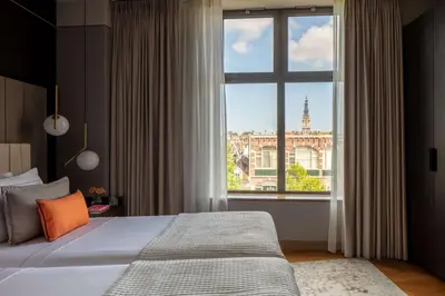 a bedroom with a bed and a large window at Anantara Grand Hotel Krasnapolsky Amsterdam in Amsterdam
