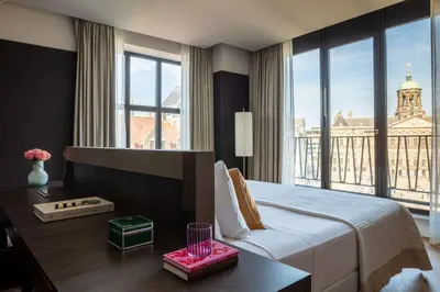 a hotel room with a bed and a large window at Anantara Grand Hotel Krasnapolsky Amsterdam in Amsterdam