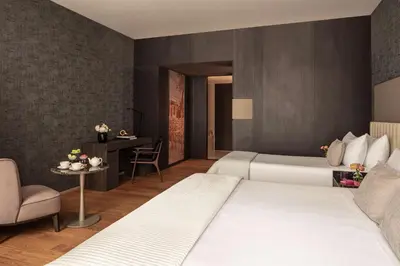 a hotel room with two beds and a chair at Anantara Grand Hotel Krasnapolsky Amsterdam in Amsterdam