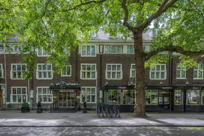 a large brick building with a tree in front of it at Apollofirst Boutique Hotel in Amsterdam