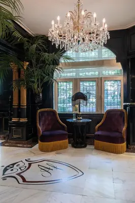 a lobby with two chairs and a table and a chandelier at Apollofirst Boutique Hotel in Amsterdam