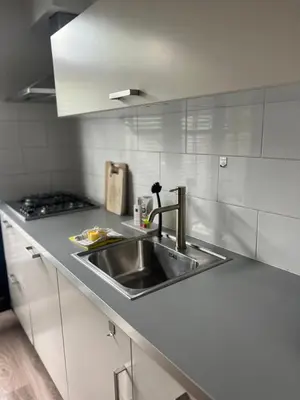 a kitchen with a stainless steel sink and white cabinets at Casa Xabia in Zaandam