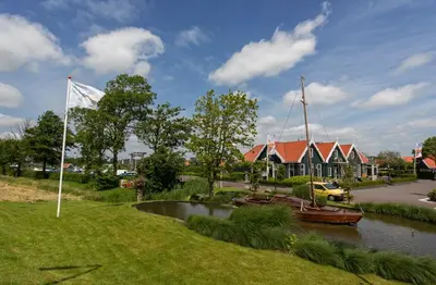 a boat in a river next to a house at De Beemster | Holiday park near Amsterdam in De Rijp