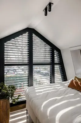 a bedroom with a white bed and a large window at Lovely private cottage near Amsterdam in Broek in Waterland