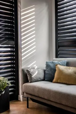 a couch in a living room with blinds at Lovely private cottage near Amsterdam in Broek in Waterland