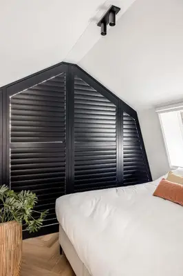 a bedroom with a large window with black shutters at Lovely private cottage near Amsterdam in Broek in Waterland