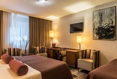 a hotel room with two beds and a desk at Hotel Amstelzicht in Amsterdam