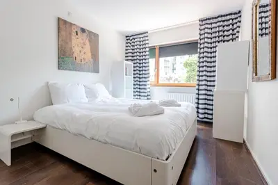 a white bedroom with a white bed and a window at Apartment Garden & Bed in Zandvoort